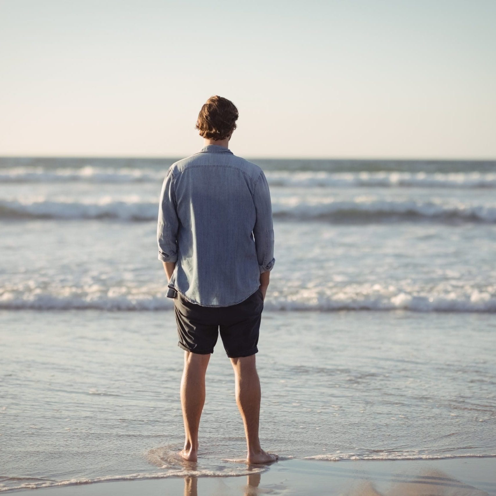 Rear view of man standing on shore at beach